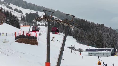 Aerial Perspective of Ski Lift Gondolas Transporting Skiers Up Snowy Mountain Slopes in the Alps