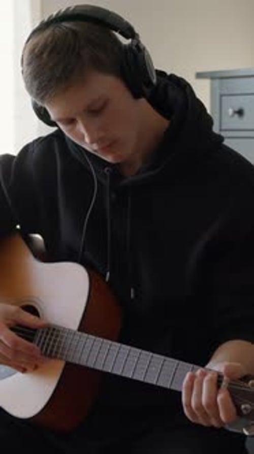 Teen Boy Plays Acoustic Guitar at Home
