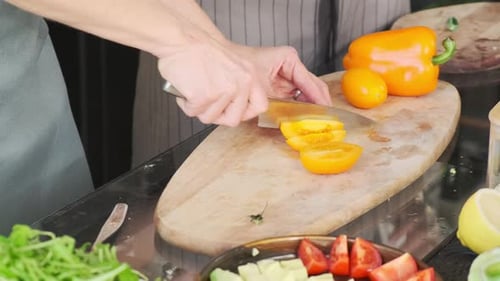 La chef coupe des tomates jaunes sur une planche à découper dans la cuisine. La fille prépare le dîner, prépare