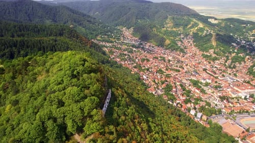 Brasov sign with tourists on the top of the hill near the city, green trees around, Romania. Old cit
