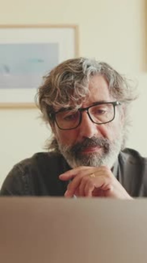 Close up, elderly man working on laptop sitting on the sofa in the living room