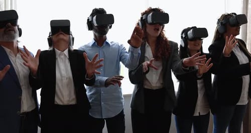 Multiracial teamwork having fun wearing virtual reality headset inside coworking office