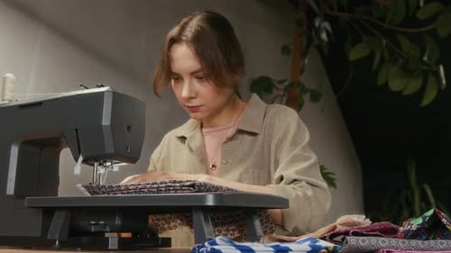 Female Tailor Seaming Garments Parts on Sewing Machine in Studio
