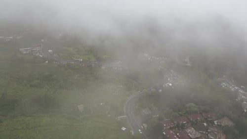 Vehicles Passing Between Houses And Green Vegetation On A Misty Day In Jakarta, Indonesia - aerial d