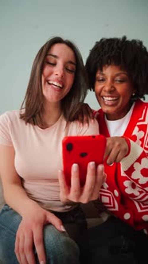 Two young women smiling looking at a cell phone