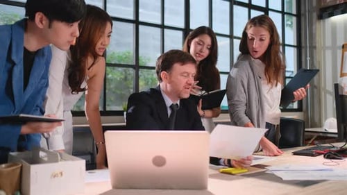 Manager explain and discuss about project in front of laptop with their team in office