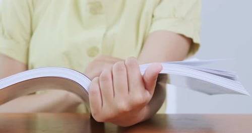 Detailed Close Up of Hands Holding and Turning Pages of an Open Book