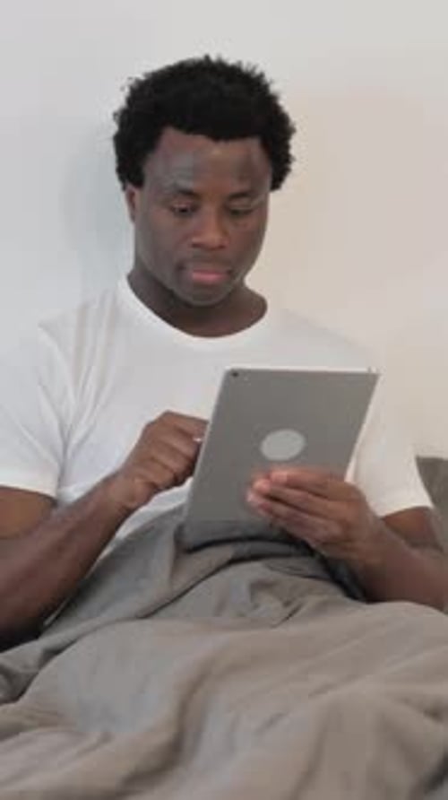 Man Using Tablet in Bed in Vertical Video
