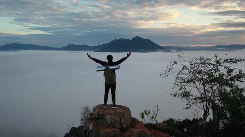 Asian Hiker Male Reaching Up Top Of Foggy Mountain And Raising His Hands