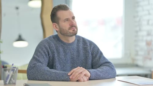 Pensive Middle Aged Man Thinking while Sitting at Work
