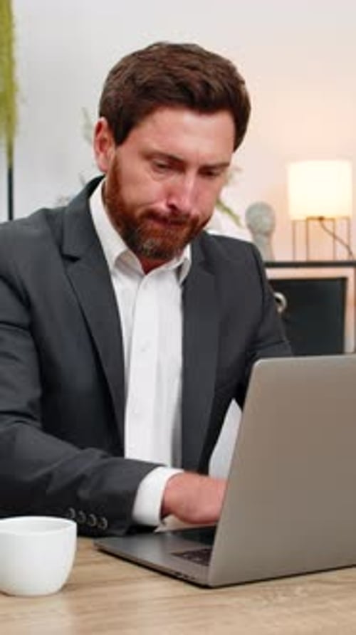 Un homme d'affaires d'âge moyen réécrit une plainte polie sur un ordinateur portable et supprime une phrase, respire le calme, tape doucement