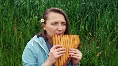 Una joven toca la panflauta en la naturaleza