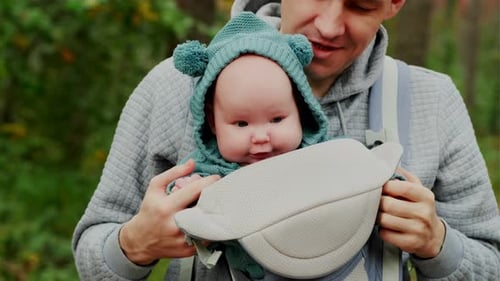 Young Father with His Newborn Baby in a Sling Walking in the Autumn Forest The Concept of a Happy