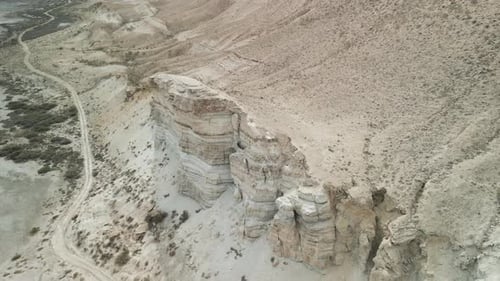Vista aérea de acantilados estratificados y una pista sinuosa cerca del lago Sudochye, Uzbekistán