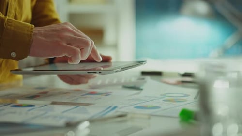 Using a modern touch tablet, a creative employee actively works in an authentic office space