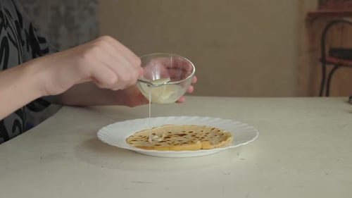 Cocinero casero vertiendo leche condensada sobre un panqueque