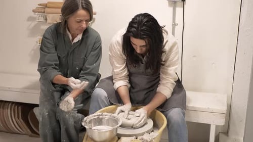 Pottery Lesson: Woman Helping Student at Wheel