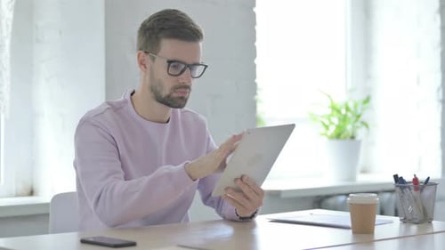 Young Man Using Tablet in Bright Office