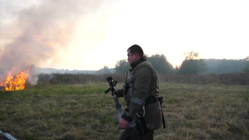 Firefighter Holding Hose Near Burning Field