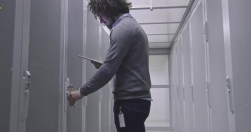 Man Opening Server Cabinet with Tablet in Data Center