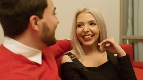 Young Couple Chatting Indoors on Red Couch
