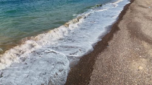 Aerial Drone View of Waves Hitting Sunny Pebble Beach Shoreline