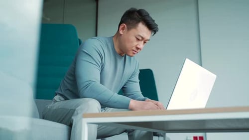 Asian male freelancer working on laptop in modern office coworking center Man student or teacher