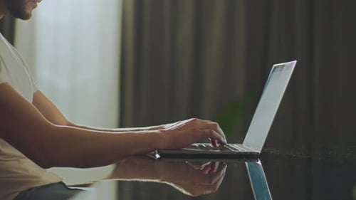 Young Adult Typing on Laptop at Home