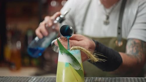 Un camarero añade alcohol a un cóctel en el bar