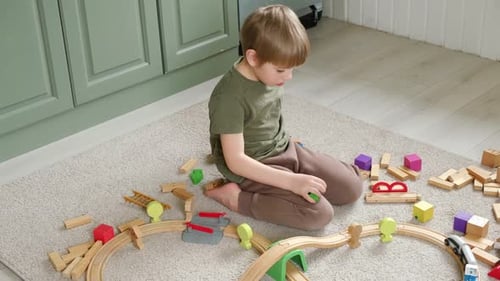 Boy Playing with Wooden Train Set on Floor