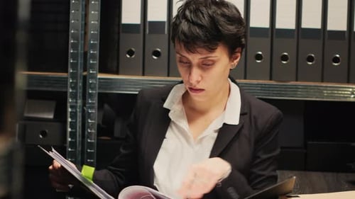 Young Woman Reviewing Documents in Office Filing Room