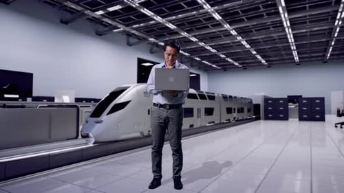 Man Using Laptop in Front of a Futuristic Train