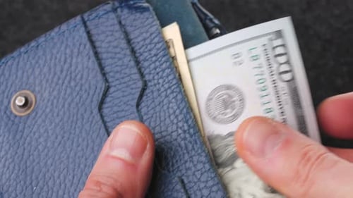 A Closeup View of Cash Being Stored in a Blue Wallet for Financial Purposes