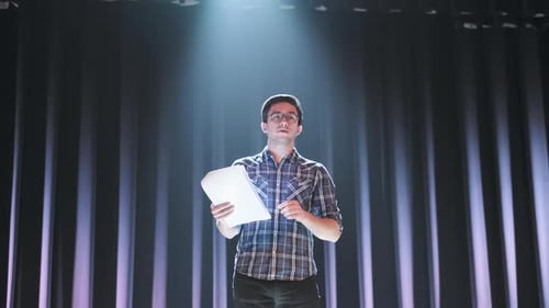 Sprecher präsentiert auf der Bühne mit Drehbuch und Mikrofon