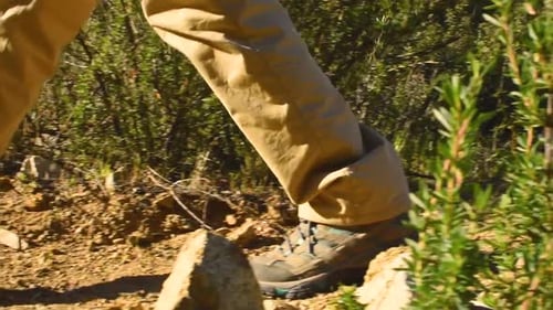 low angle close up, of feet walking on dirt, pan left camera movement
