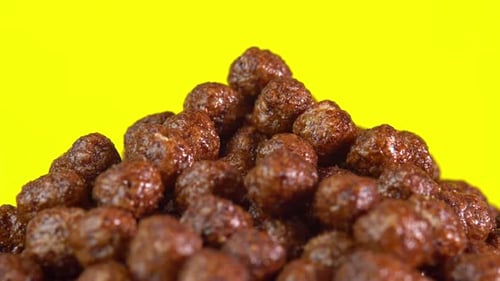 Pile of Chocolate Breakfast Cereal Puffs Against Yellow