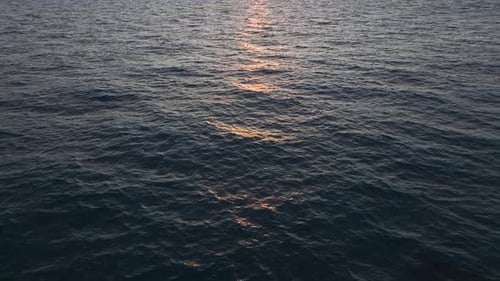 Aerial Video Vibrant Sunset Rays Reflecting on Textured Ocean Waters with Gentle Ripples
