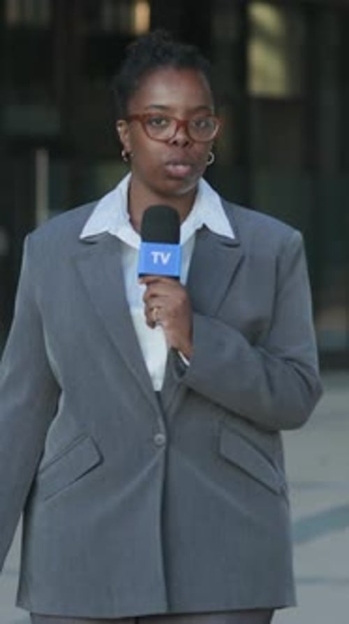 Woman Reporting News with Microphone on City Street