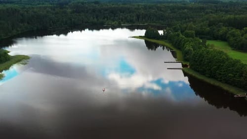 Lake with sky reflection and Inflatable water toy float, green forest around