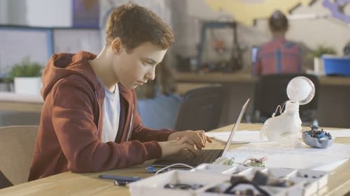 Smart Young Boy Works on a Laptop For His New Project in His Computer Science Class. Other Children