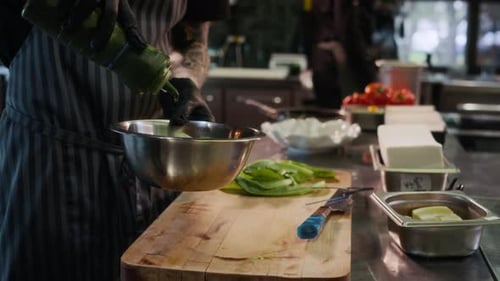 Chef Adding Dressing to Salad in Restaurant Kitchen