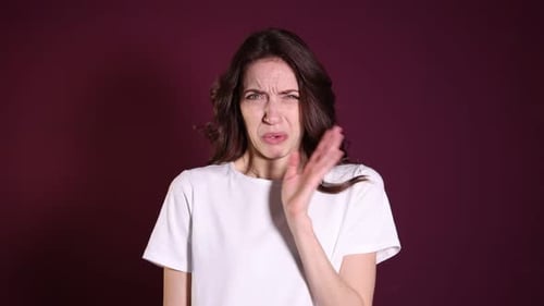 Woman suffering from bad smell on burgundy background