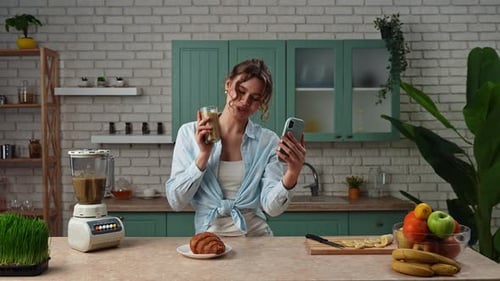 Woman Video Chatting in Kitchen With Smoothie