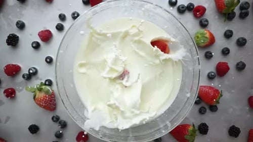 A Bowl of Milk Adorned with Strawberries and Blueberries on a Table