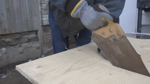 A Man Wearing Gloves Is Cutting The Pencil Line On The Wood Planks - Medium shot