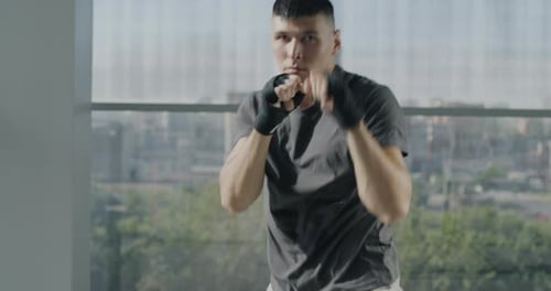 Slow Motion Portrait of Motivated Young Sportsman Training in Gym Throwing Punches with Wrapped
