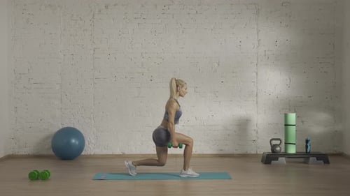 Fit Woman Lunging with Dumbbells in Studio