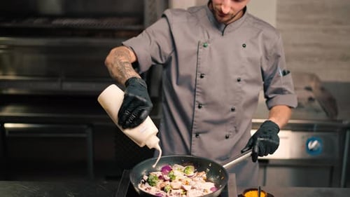 Chef Adding Creamy Sauce to Seafood and Vegetables