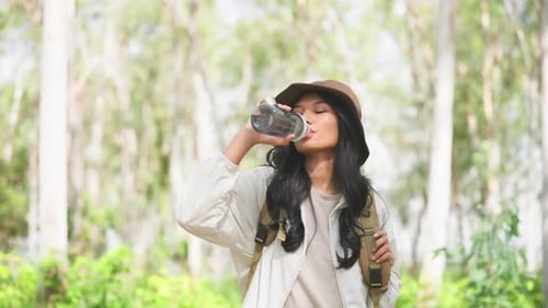 Woman Drinks Water While Hiking in Nature