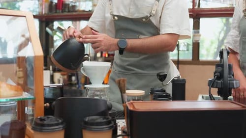 Close up of professional barista or waiter working in coffeehouse shop.